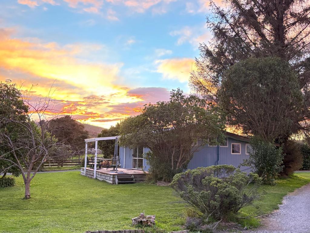 a house in a yard with a sunset at Flat Hills Tourist Park in Ruahine