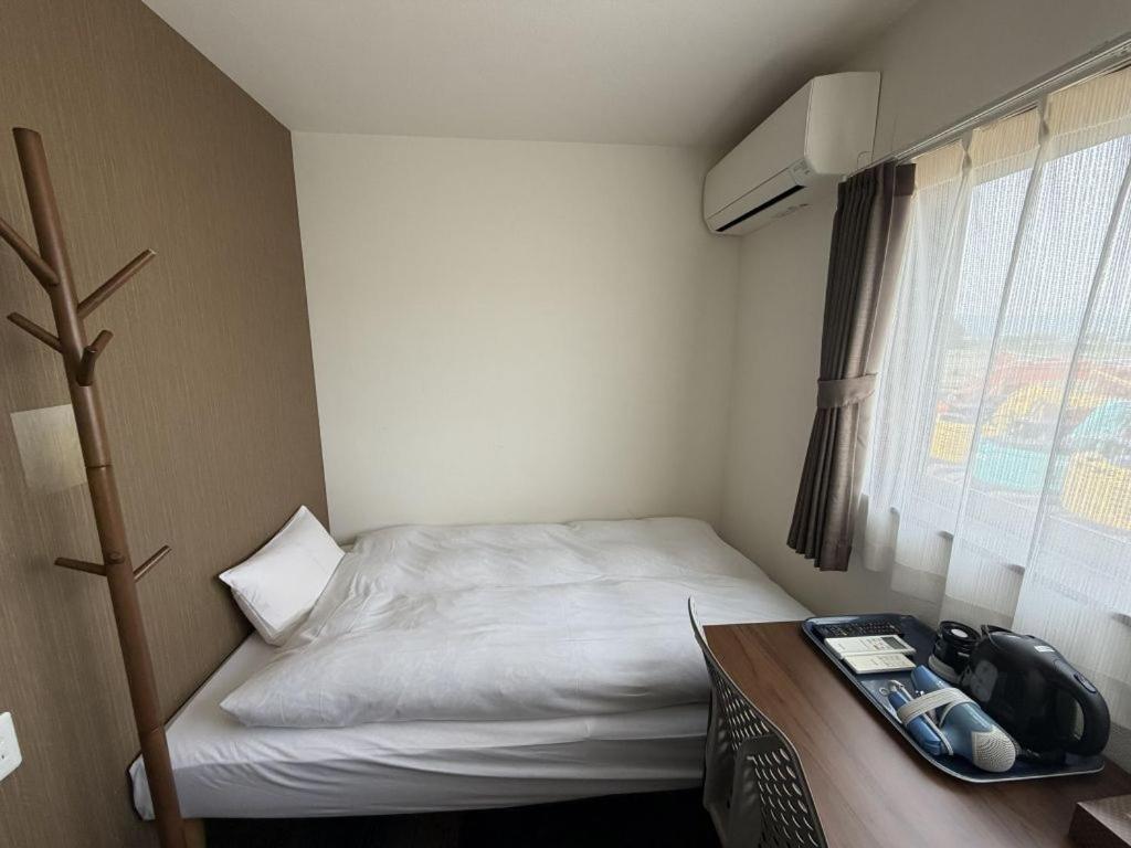 a small room with a bed and a desk and a window at Hotel The Namie Terrace in Namie