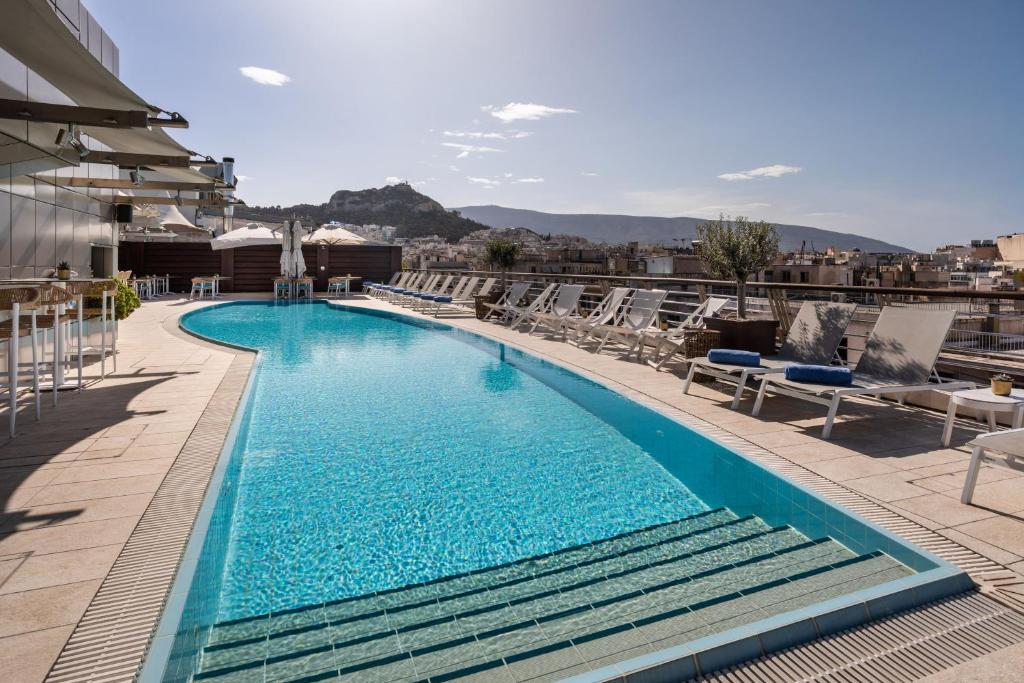 a swimming pool on top of a building with chairs at Meliá Athens in Athens