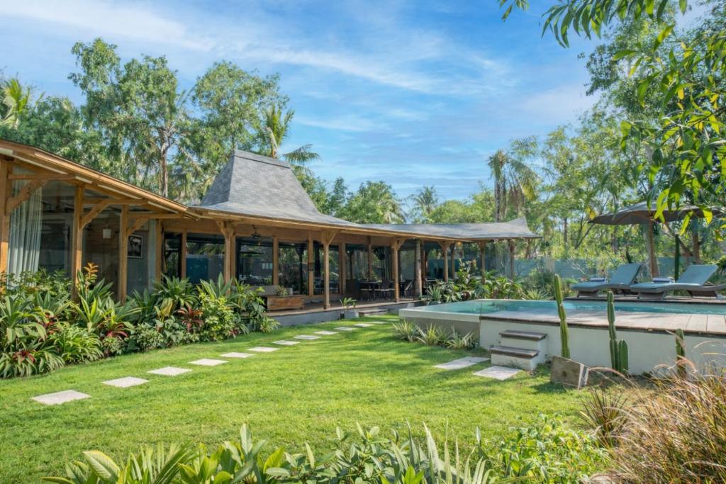 an exterior view of a house with a swimming pool at Villa Harimau-Original Joglo style 3B with pool in Gili Trawangan