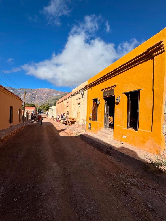 a yellow building on the side of a dirt road at Hostería Los Morteros in Purmamarca