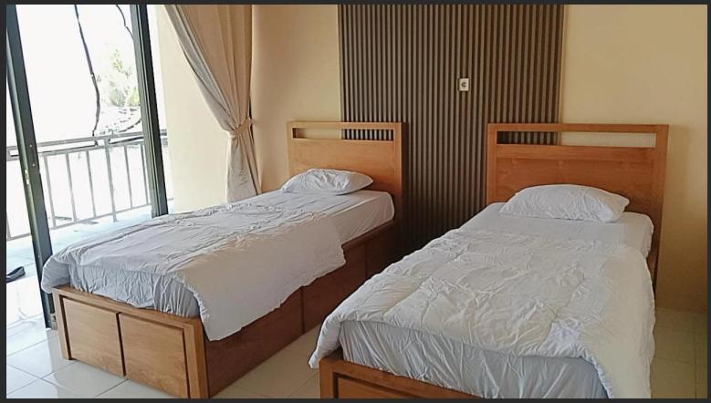two beds in a room with a window at Blue Rose Resort & Dive Center in Pattimura Airport