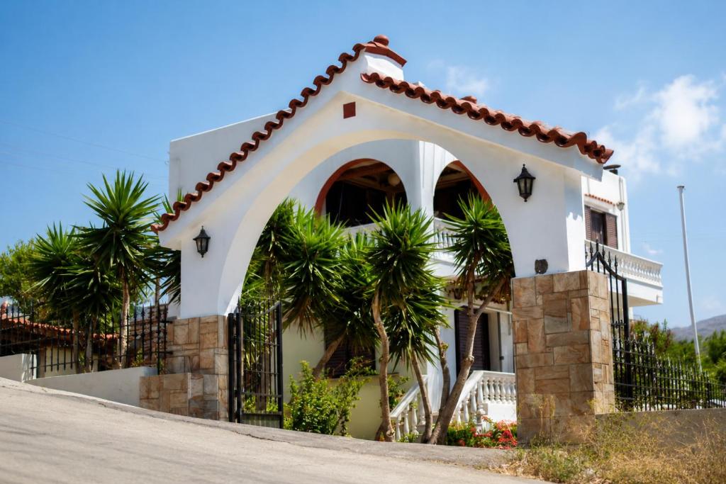 a house with a gate and palm trees at Stelios Zalonis Apartments in Tinos
