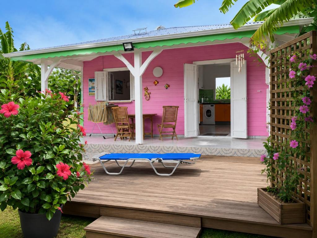 a pink house with a table on a wooden deck at O baobab in Saint-François