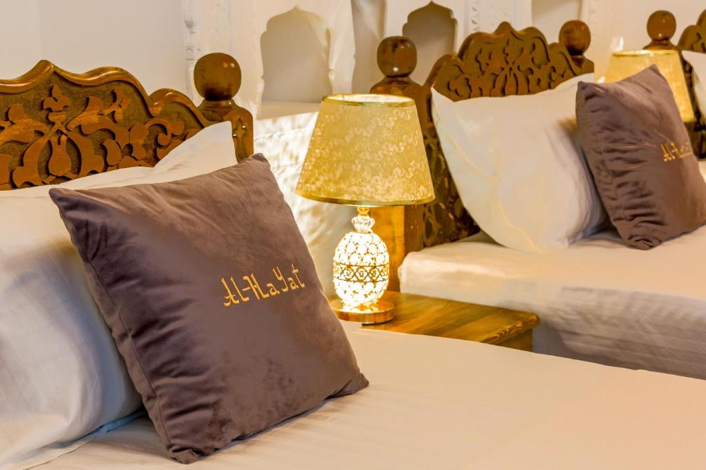 a bedroom with two beds with pillows and a lamp at AL-HAYAT in Bukhara