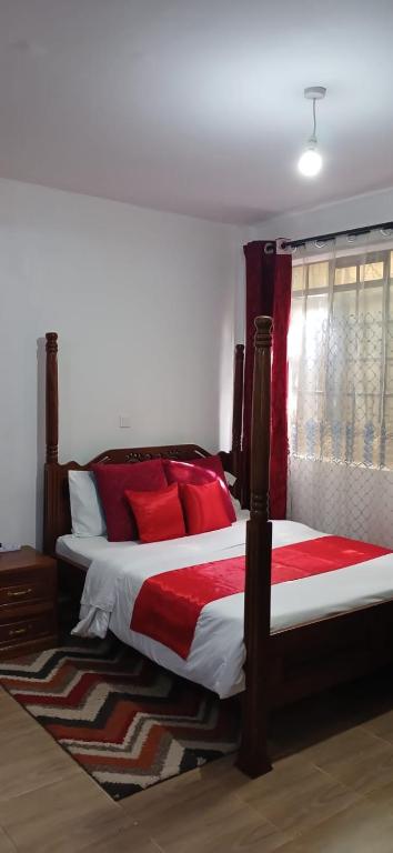 a bedroom with a large bed with red pillows at Sunny Studio Kikuyu Town in Kikuyu