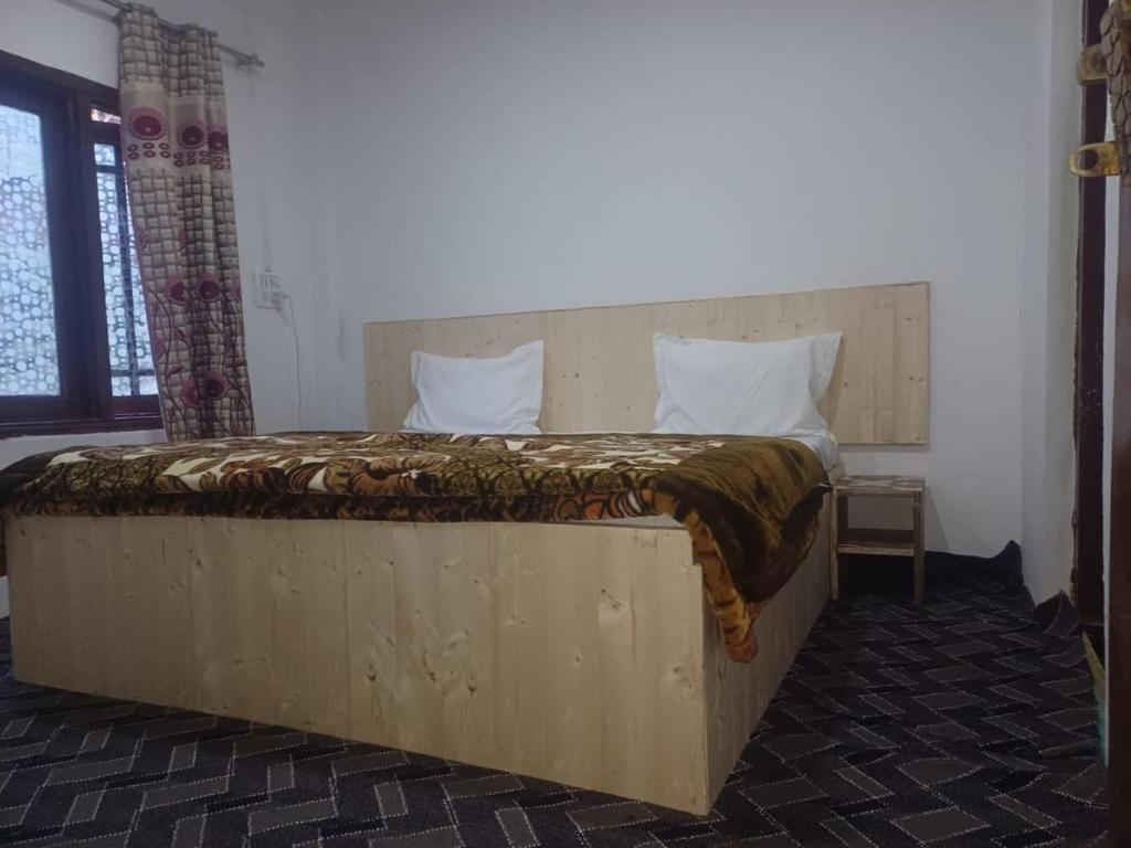 a bedroom with a large bed with a wooden headboard at SnowCrest Cottage in Pahalgām