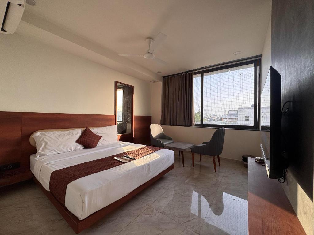 a hotel room with a bed and a desk and a window at Hotel Aqua in Rajkot