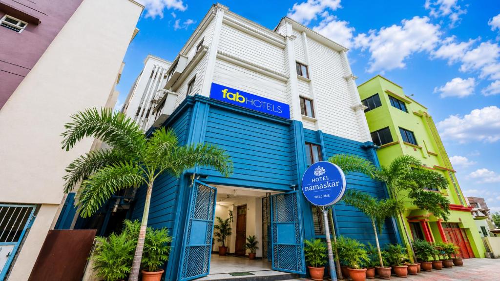 a blue and white building with palm trees in front at Fabhotel Namaskar - Nr Udayagiri and Khandagiri caves in Bhubaneshwar
