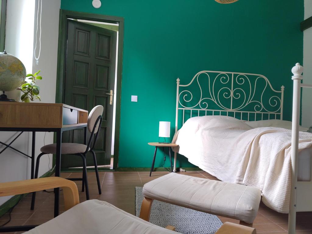 a bedroom with a green wall with a bed and a desk at Mackó Kuckó Verőce in Kismaros
