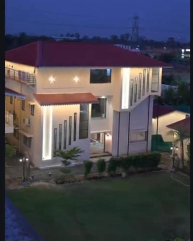 a large white house with a lawn in front of it at Nicolas Farm & Resort in Mansar