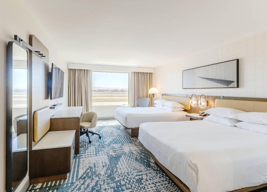 a hotel room with two beds and a desk at Radisson Hotel Santa Maria in Santa Maria