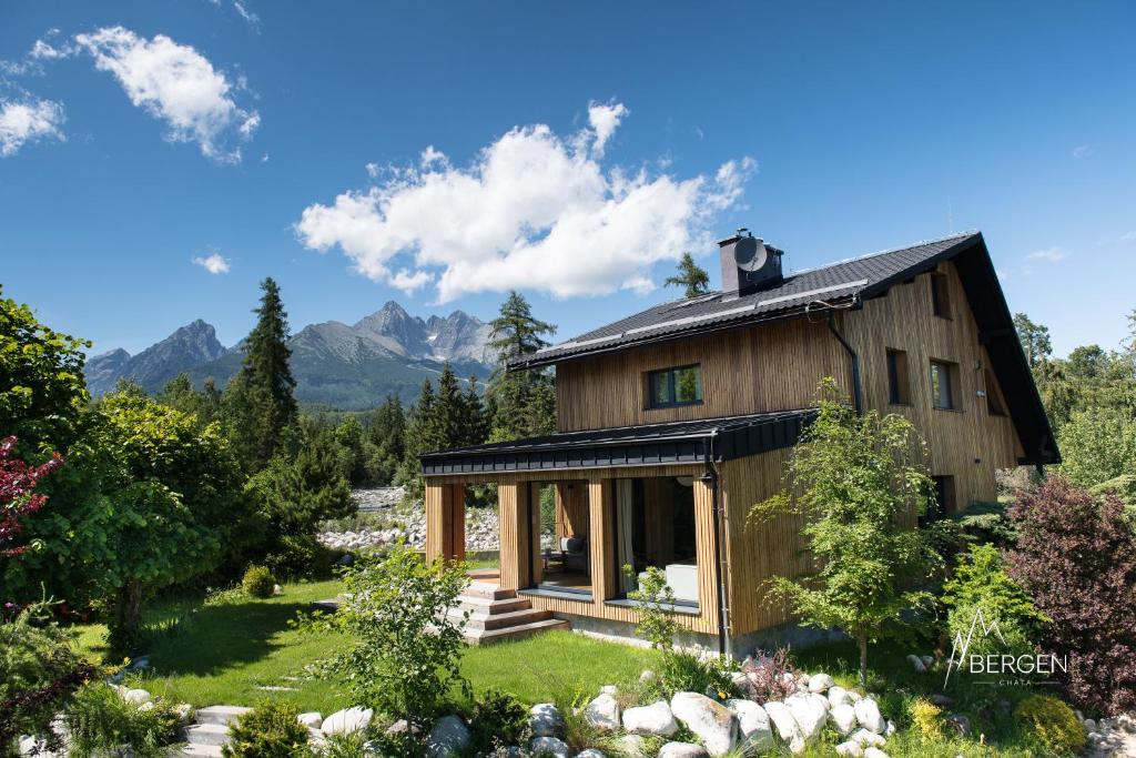 a wooden house with mountains in the background at Chata Bergen in Vysoké Tatry