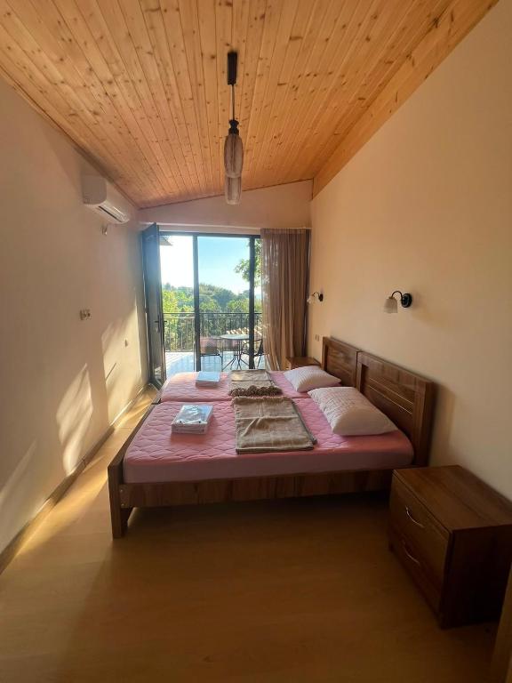 a large bed in a room with a large window at Park & Sea Townhouse in Makhinjauri