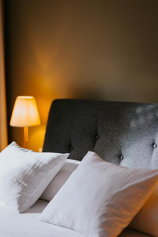 a bedroom with a bed with white pillows and a lamp at Lucy Villa in Băile Tuşnad