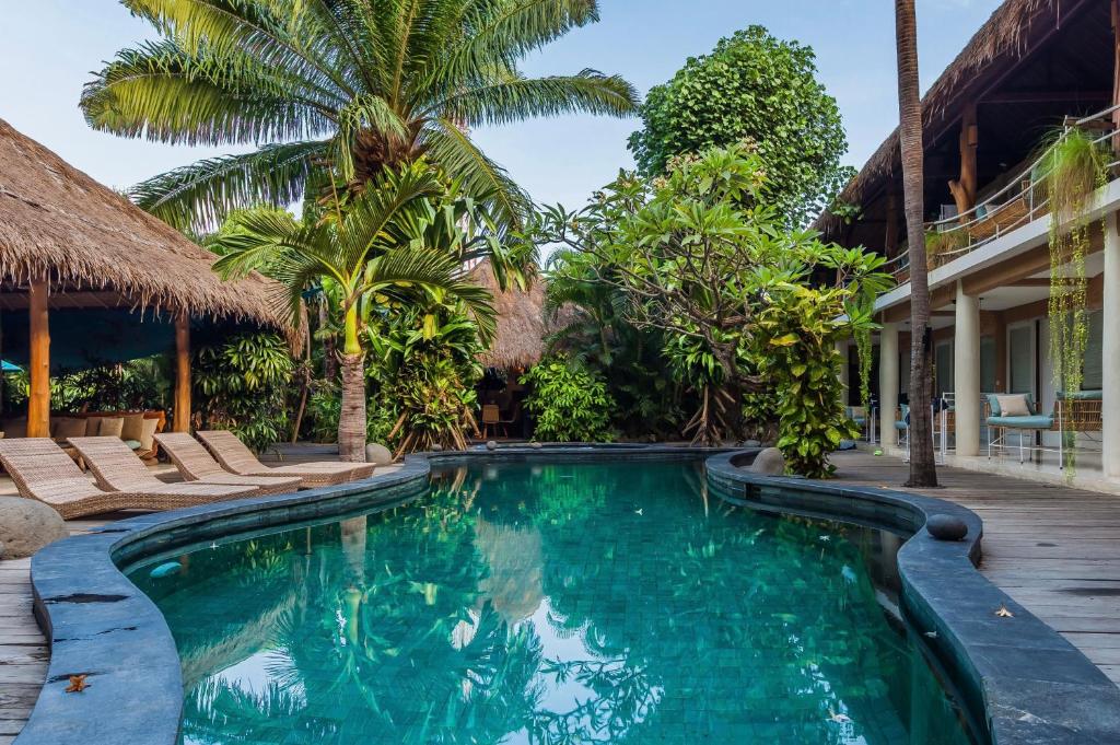 a swimming pool in a resort with palm trees at Kima Surf Camp Bali Seminyak in Seminyak