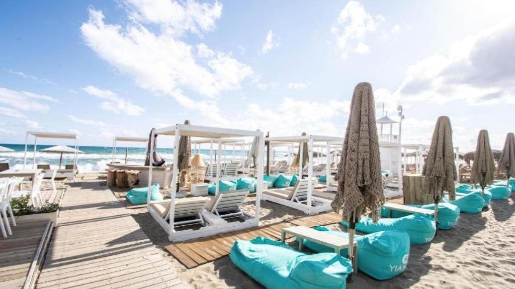 a group of lounge chairs and umbrellas on the beach at Apartment Simply 203 in Gázion