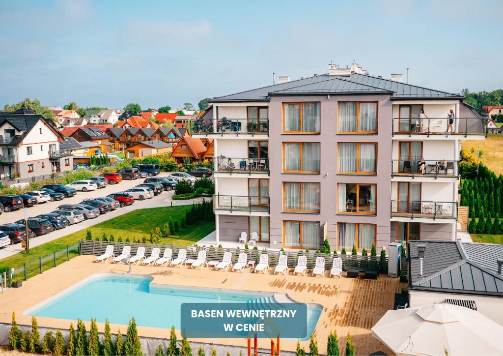 a hotel with a swimming pool and a parking lot at Blu Apartments in Sarbinowo