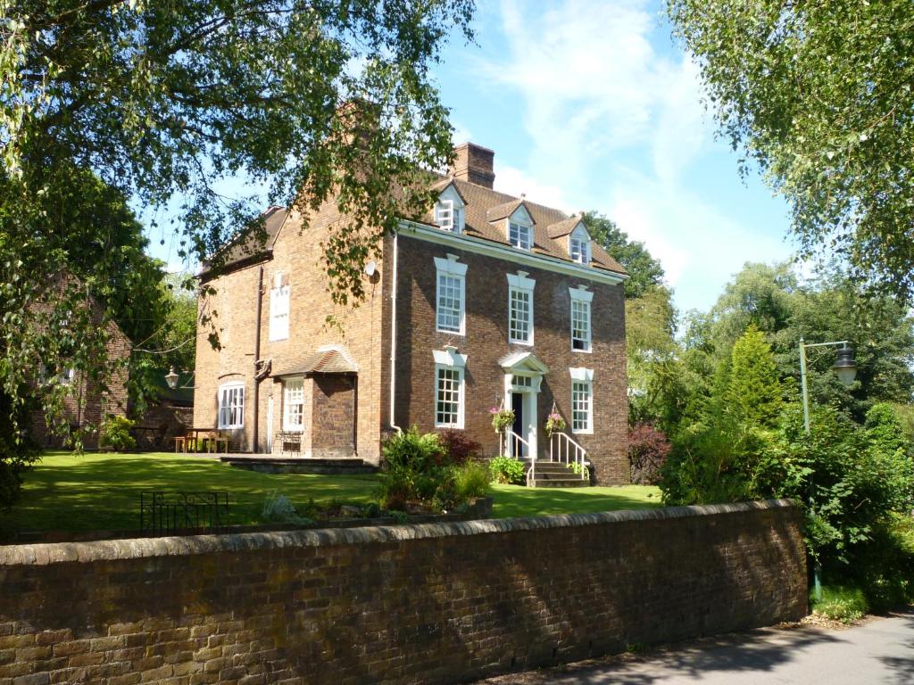 a large brick house with a stone wall at Calcutts House in Ironbridge