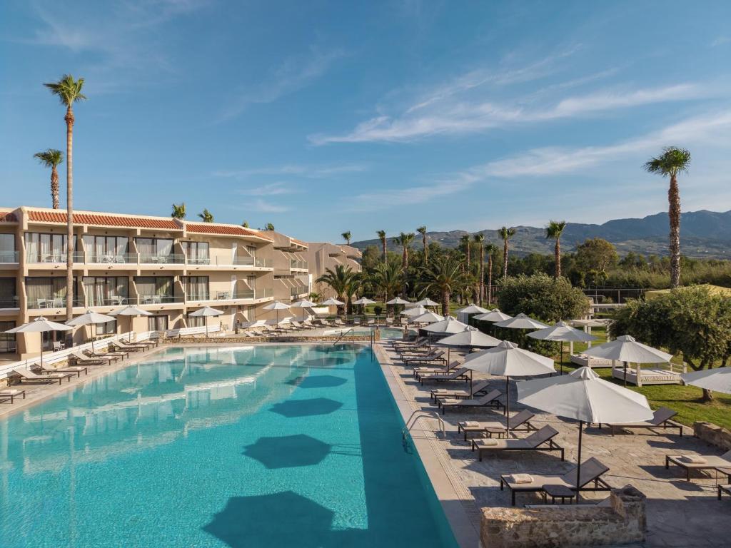 a swimming pool with chairs and umbrellas next to a hotel at Atlantica Thalassa Hotel in Kos