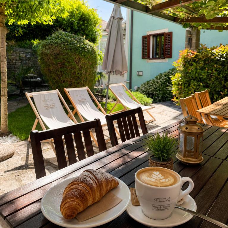 a table with a cup of coffee and a croissant at Miracolo di Mare Retro in Piran