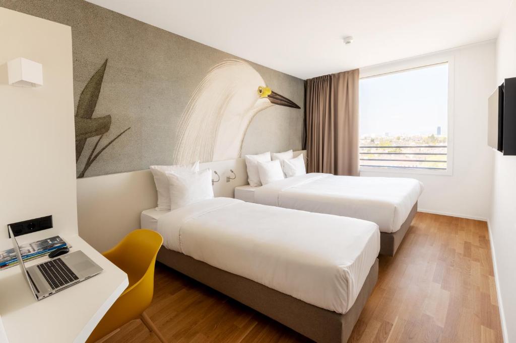 a hotel room with two beds and a desk with a laptop at B&B HOTEL Basel in Basel