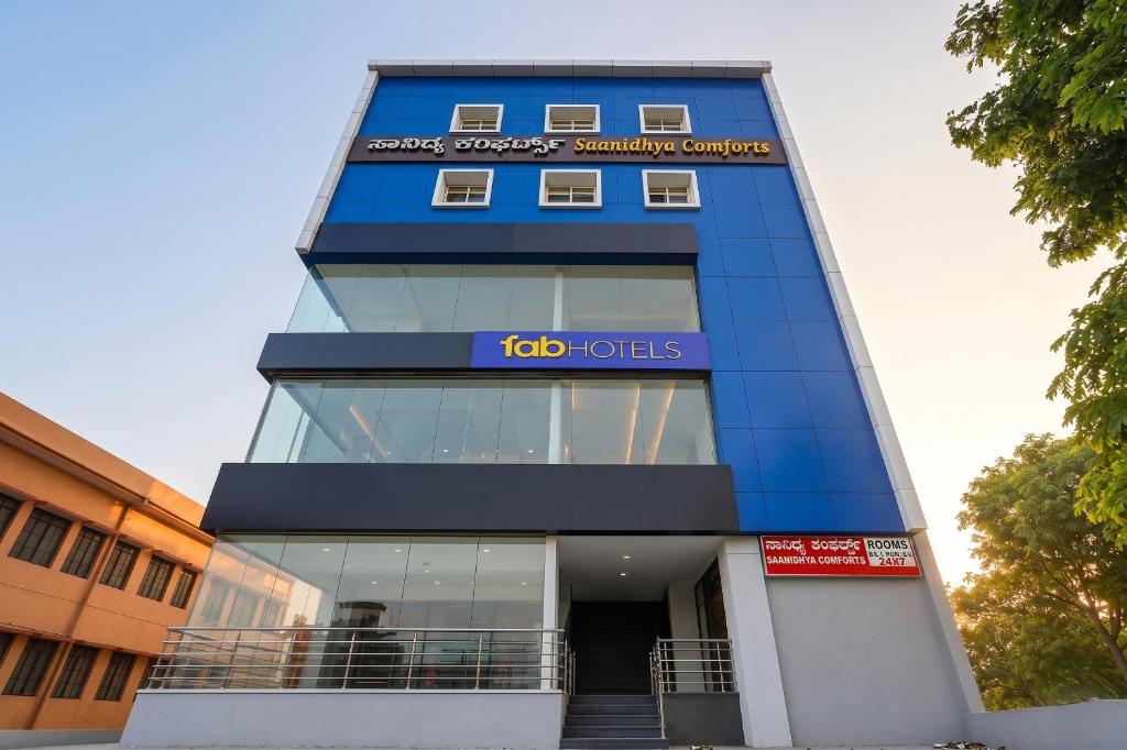 a tall blue building with a sign on it at FabHotel Saanidhya Comforts - Tumkur Road in Kunigal
