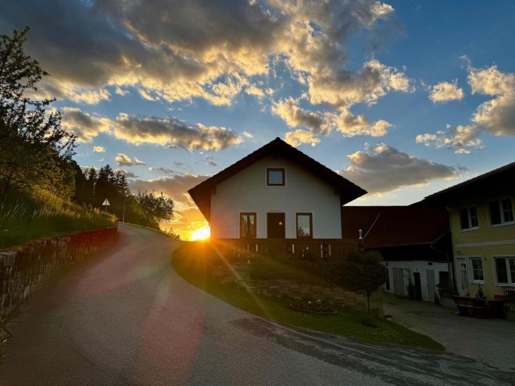 a house on the side of a road with the sunset at Ferienhaus am Bauernhof mit Terrasse nähe Wexl Arena in Sankt Corona am Wechsel