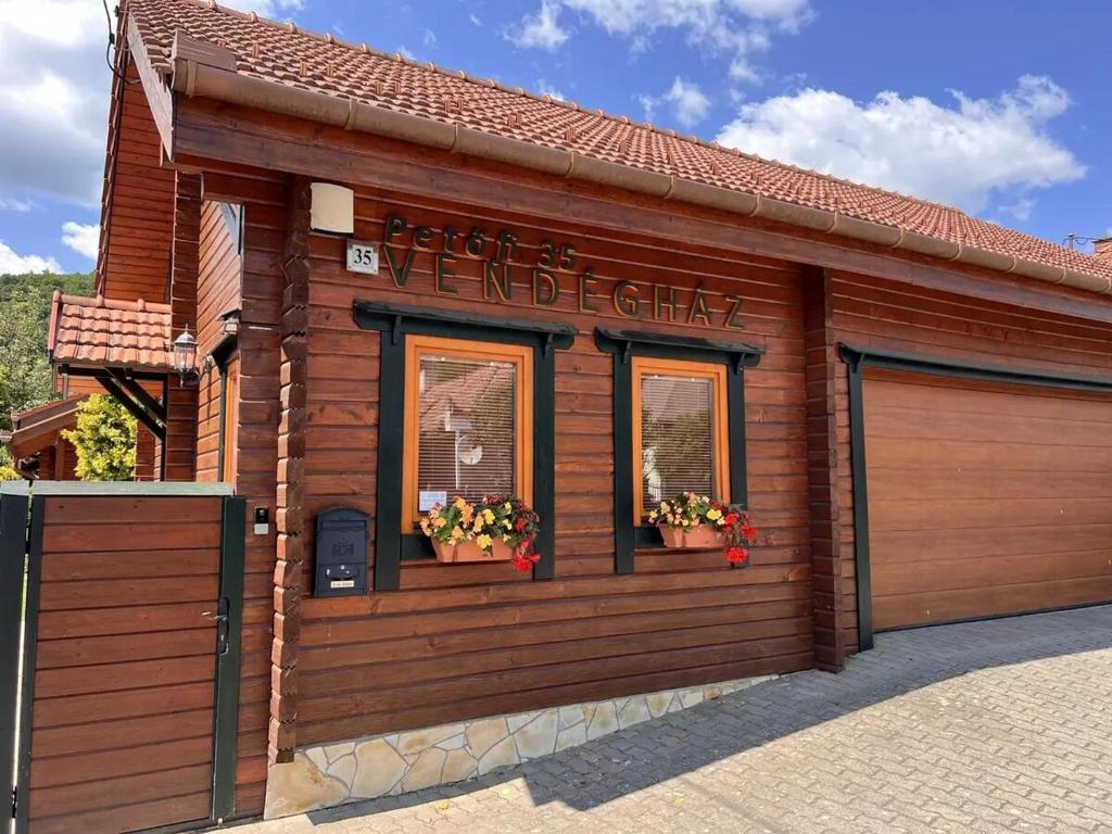 a wooden building with two windows and a garage at Petőfi 35 Vendégház in Sirok