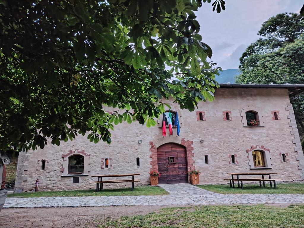 a stone building with two benches in front of it at Rifugio Forte di Machaby in Arnad
