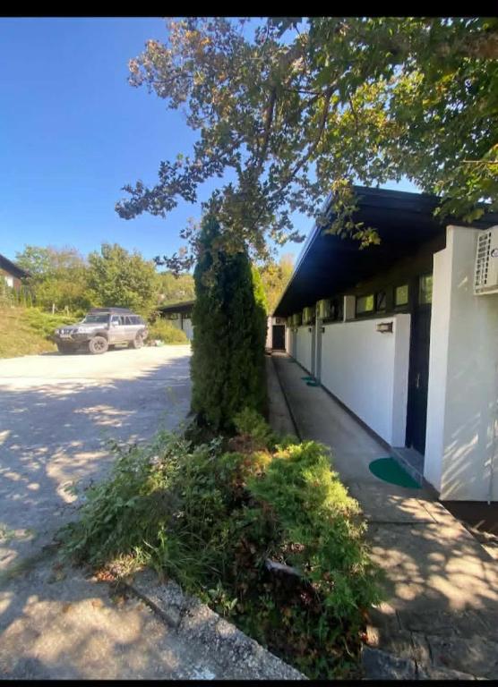 a tree in front of a building with a garage at Camp Rooms in Jajce