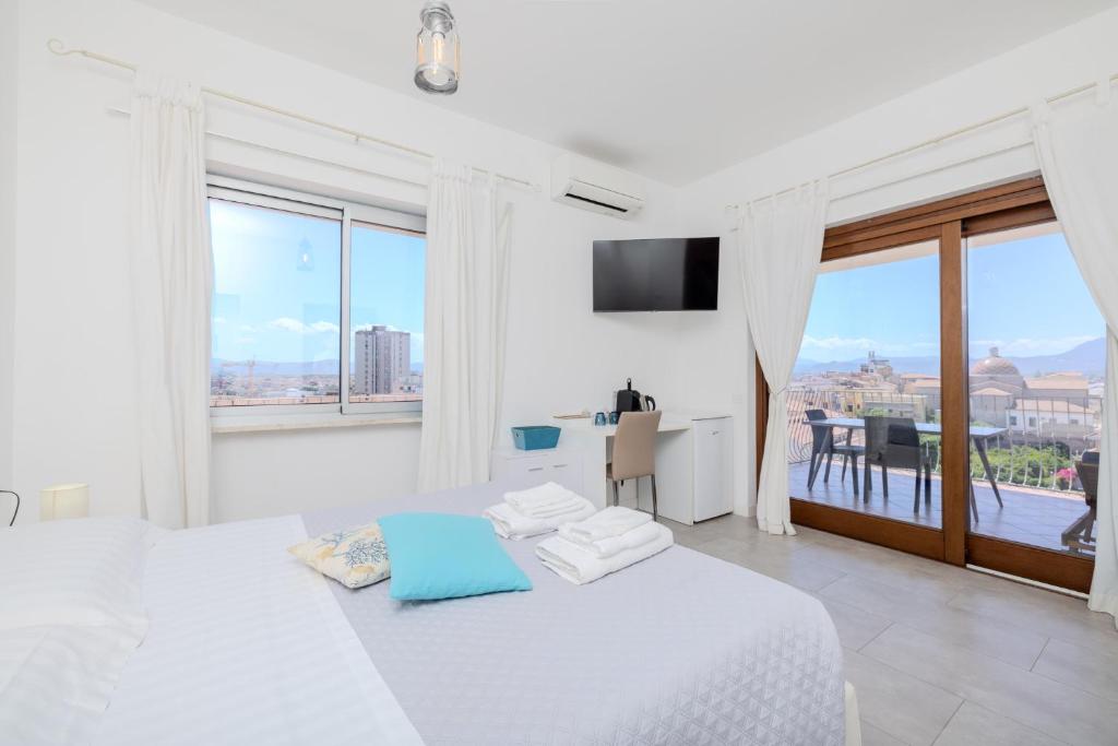 a white bedroom with a white bed and a large window at Marysel Rooms in Olbia