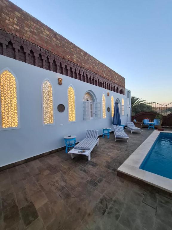 a patio with chairs and a swimming pool at Nefertiti Guest House in ‘Ezbet Abu Ḥabashi