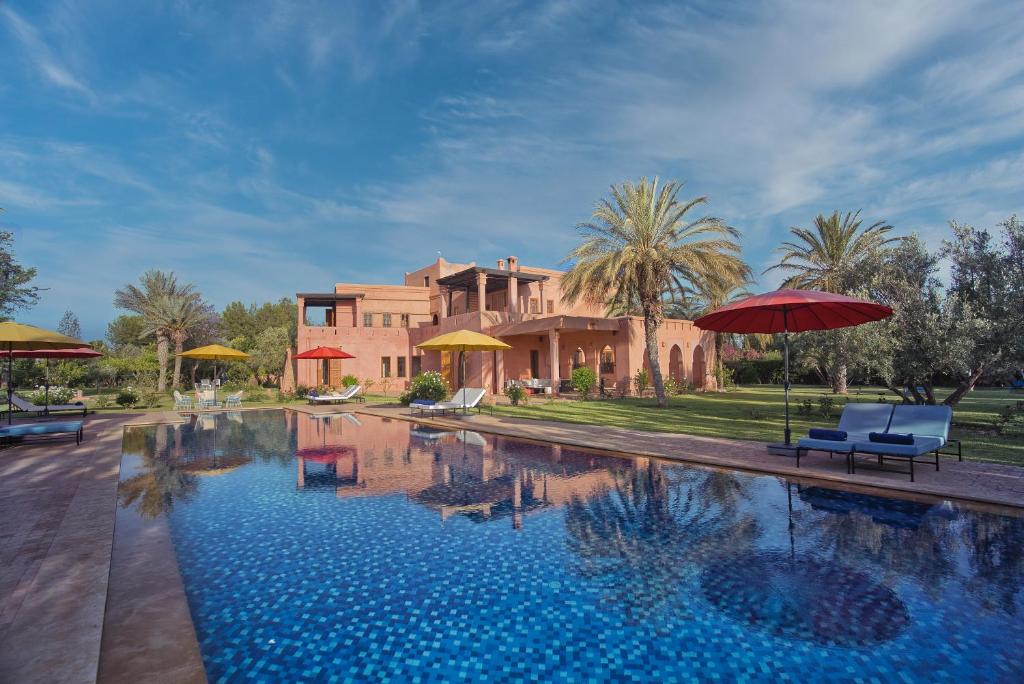 a house with a swimming pool with umbrellas at Domaine 3 Riads in Marrakesh