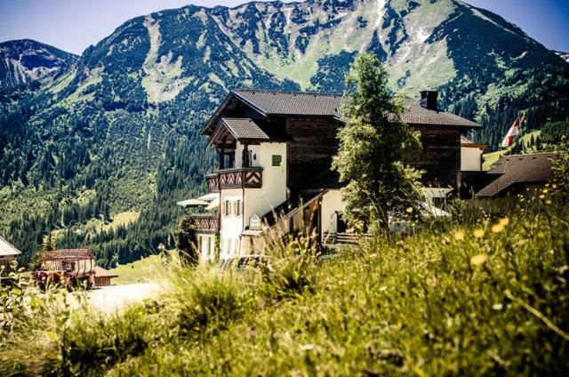a building on a hill with a mountain in the background at Berghotel Zugspitzblick in Zöblen