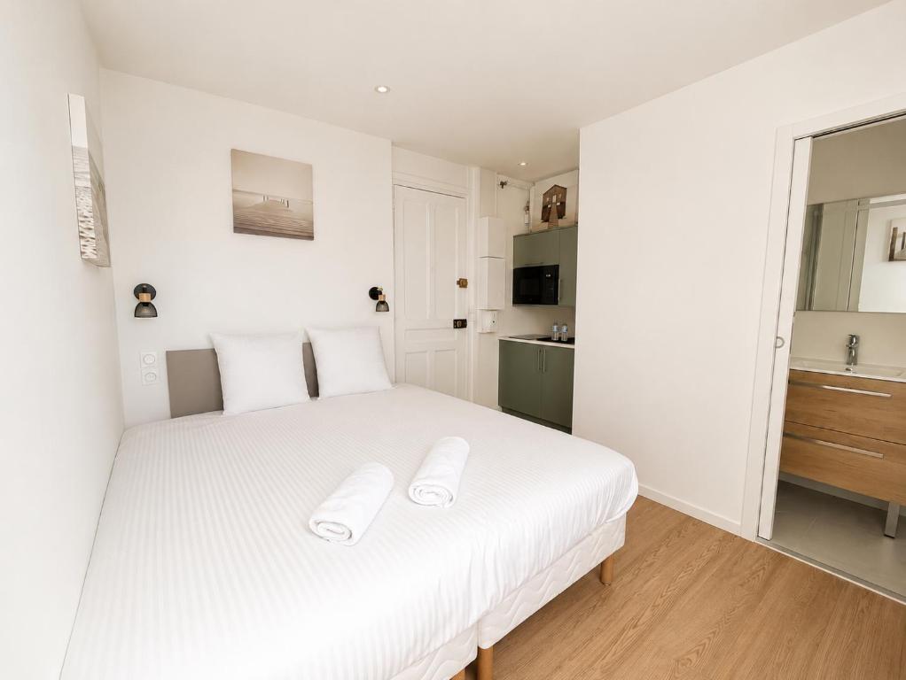 a bedroom with a white bed with white pillows at La Chambre Deauvillaise in Deauville