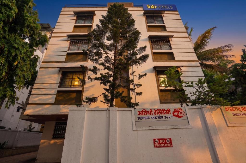 a tall building with a tree in front of it at FabHotel Ateethi Residency in Pune