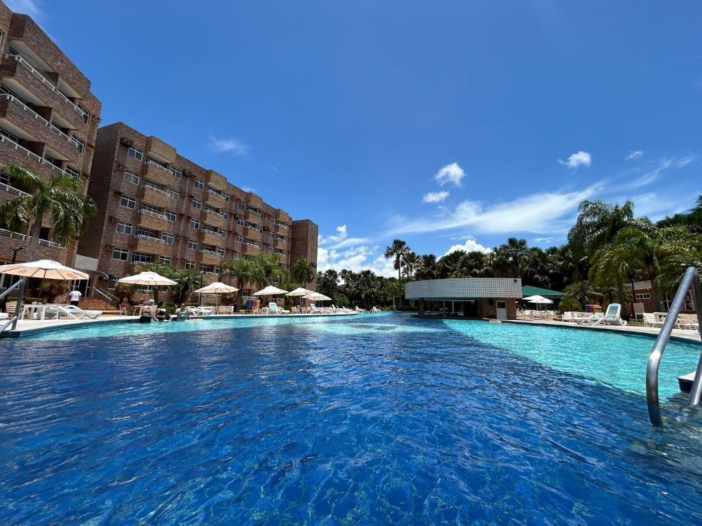 a large swimming pool with chairs and umbrellas at Gran Lençóis Flat Residence - Flat 302 in Barreirinhas