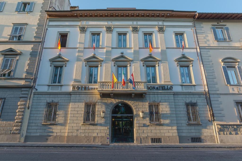 un bâtiment avec plusieurs drapeaux devant lui dans l'établissement Hotel Donatello, à Florence