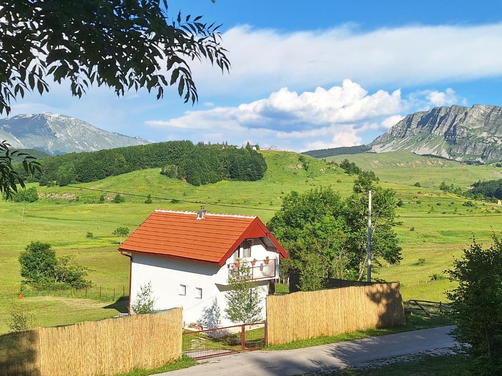 a small house with an orange roof in a field at Horizont Cemerno in Podborina