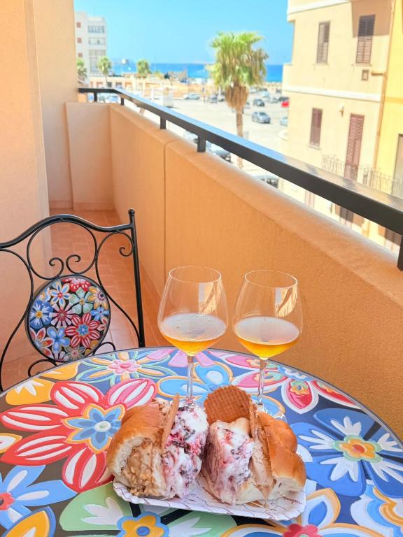a table with two glasses of wine and a plate of food at Home Sisters in Trapani