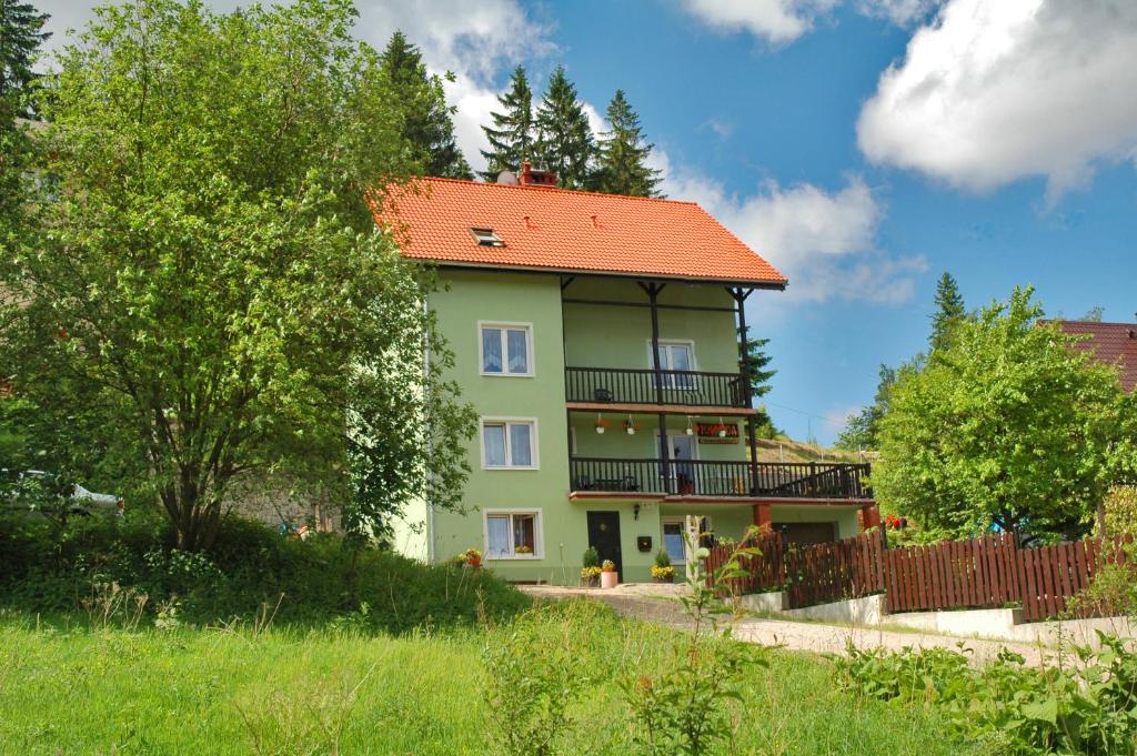 シュクラルスカ・ポレンバにあるPokoje Gościnne Magdaのオレンジ色の屋根の緑家