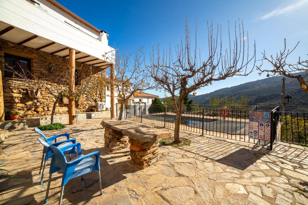 two blue chairs and a bench in front of a building at Yerbaluisa in Laroya