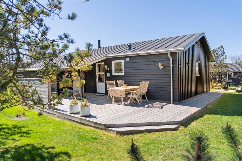 a wooden deck with a table in a backyard at 136-Snedsted-Lykkens-Hab-23 in Snedsted