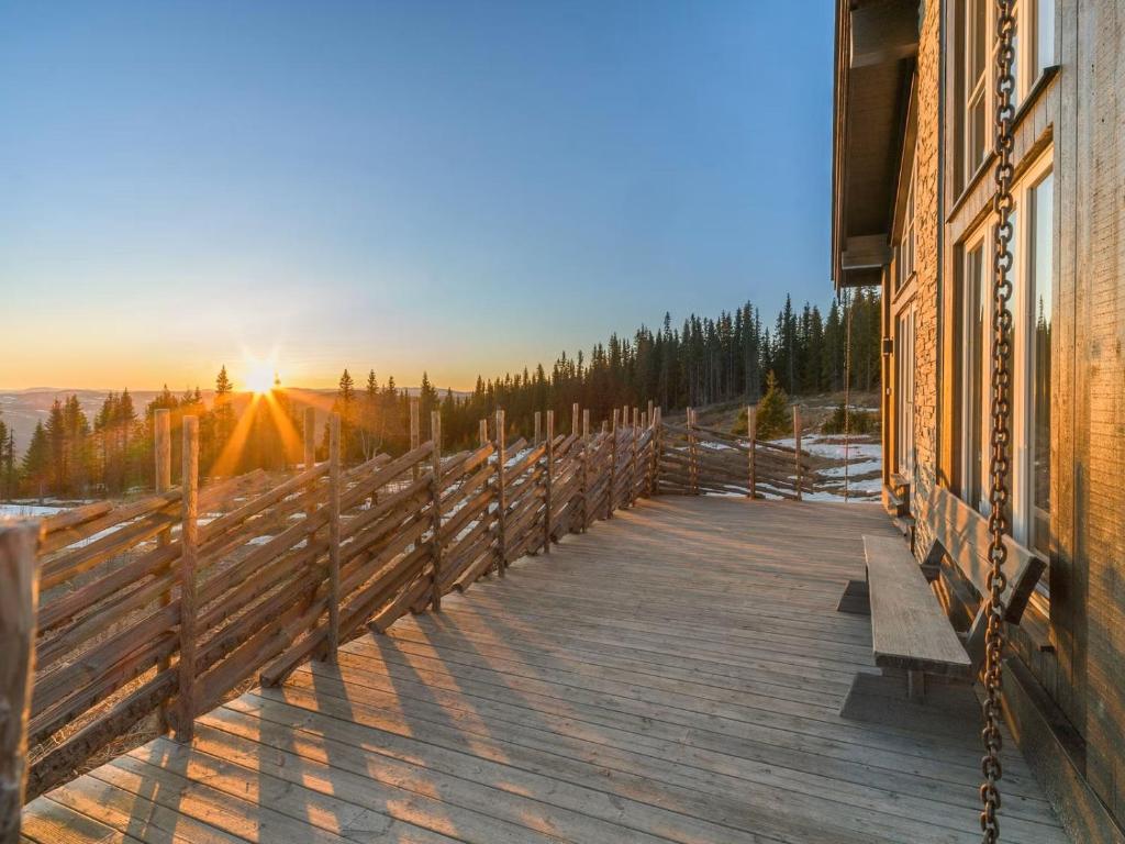 a wooden deck with a bench on a building with the sunset at Ski cabin in Hafjell in Øyer