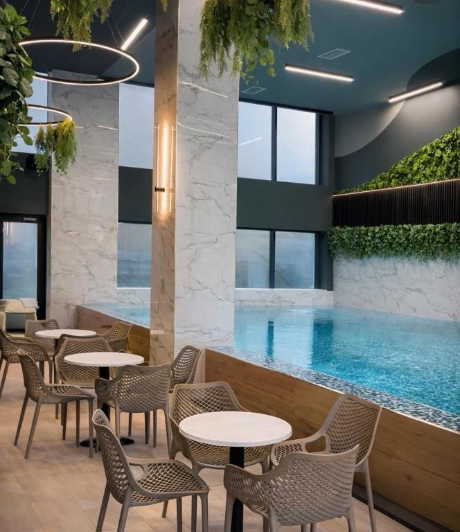 a restaurant with a pool and tables and chairs at Tesla Palace III in Kragujevac