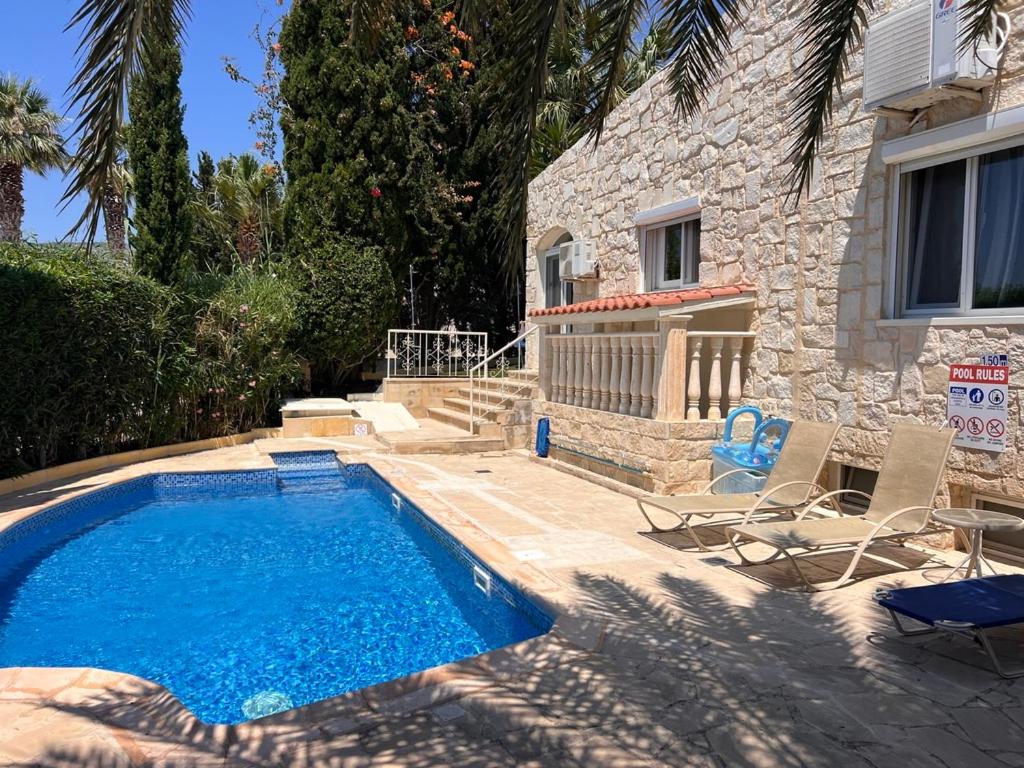 a swimming pool in front of a house with chairs at Villa Neyla Four bedroom Coral Bay Beach front in Coral Bay