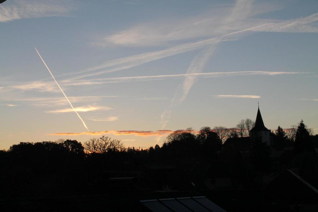 einen Sonnenuntergang mit einer Kirche und einem Kreuz am Himmel in der Unterkunft Ferienwohnung Sonnengruss in Nettersheim