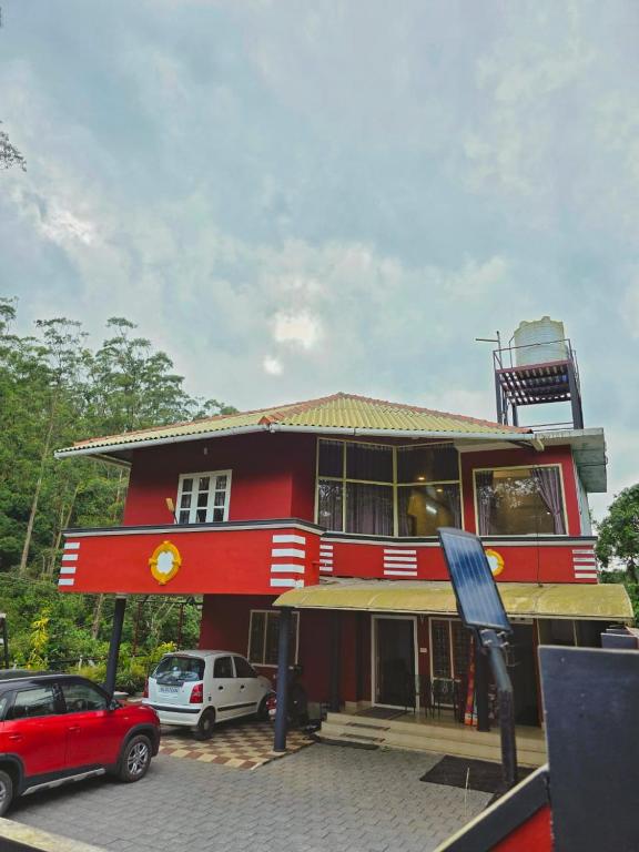 a red building with cars parked in front of it at Pine ridge homestay kuttikanam in Pīrmed