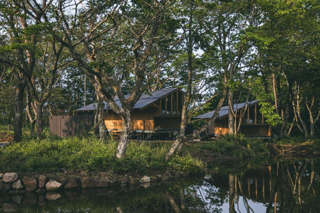 a cabin in the woods next to a body of water at Earthboat Nasu - Glamping Cabin with Private Wood-Fired Sauna & Onsen, Pet-Friendly & Cage-Free in Nasu